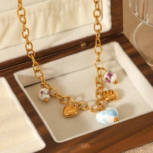 Gold chain necklace with floral beads and heart pendants in a wooden jewelry box