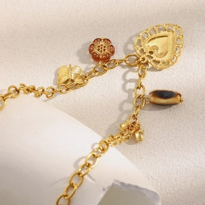 Close-up of 18K gold plated chain with hollow heart pendant and amber flower charm