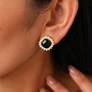 Close-up of square black stone earring with halo of sparkling crystals on earlobe