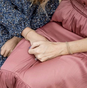 Close-up of a model wearing stacked gold beaded bracelets with a floral dress
