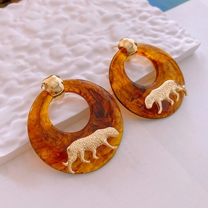 Detail shot of amber resin hoop earrings with golden leopard accent and silver needles