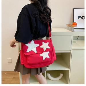 Detail of red canvas crossbody bag with white sequin stars worn by model
