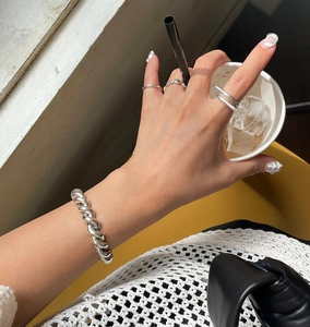 Detail of minimalist 925 sterling silver geometric rings and twisted bangle on hand