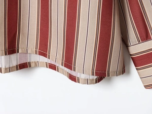 Détail des coutures d'une chemise à rayures et texture de tissu tissé rouge et beige