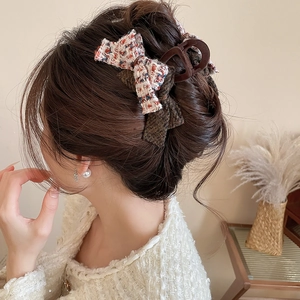 Detail of tweed bow hair claw clip worn on hair showing textured fabric and resin material