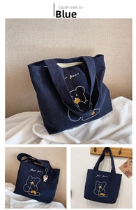 Detail of blue corduroy tote bag featuring white bear pattern and cow pendant accessory