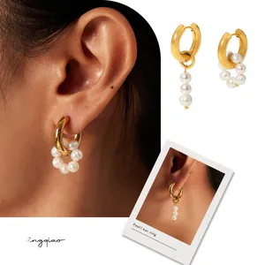Detail of asymmetric gold hoop earrings with white natural freshwater pearl pendants