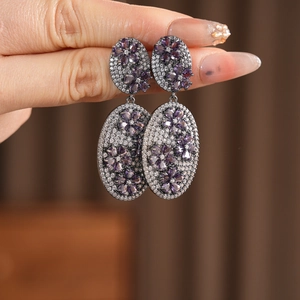 Macro shot of vintage floral oval drop earrings with purple zircon and black gold finish