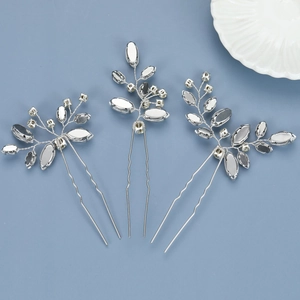 Detailed view of three silver leaf crystal hair pins on light blue background