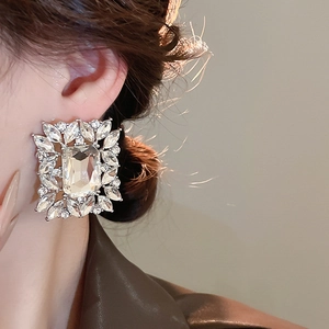 Macro detail of luxury silver leaf square earrings with sparkling crystals on model