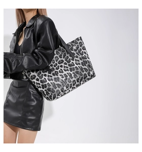 Detail of trendy black and white leopard print tote bag styled with a black leather jacket