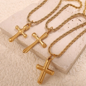 Vintage 18K gold plated stainless steel cross pendant necklaces on white stone display