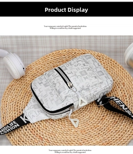 Detail of white nylon crossbody bag with strawberry print and letter patterned strap