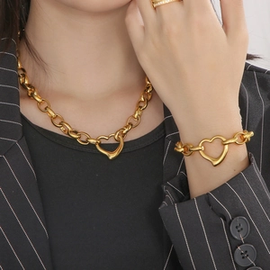 Golden stainless steel heart pendant necklace and bracelet set on model in a suit
