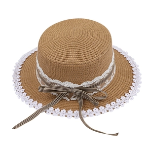 Brown straw sun hat with white lace trim and black gingham bow ribbon on a white background