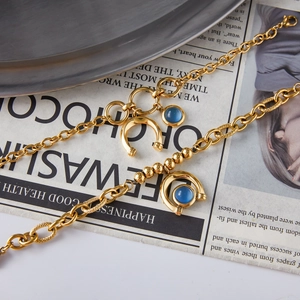 Gold titanium steel horseshoe bracelet with blue resin stone on vintage newspaper