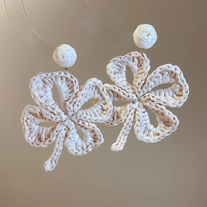 Detailed view of woven raffia flower earrings in beige with handmade texture