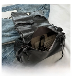 Detail view of the black leather bag's internal capacity with phone, glasses and card holder