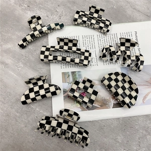 Top view of large black and white checkerboard hair claws on a fashion magazine