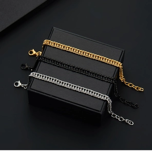 Detailed view of three punk Cuban chain bracelets in gold, black, and silver on a box