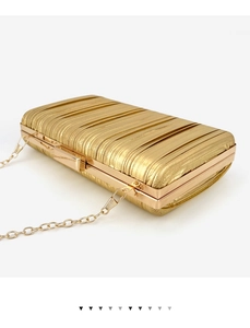 Detail view of golden pleated evening clutch bag with elegant metal chain strap and top clasp