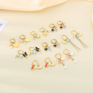 Golden heart earrings set with pearls, butterflies, and tassels on silk fabric