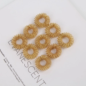 Detail of nine gold spring finger massager rings arranged on minimalist white cardstock