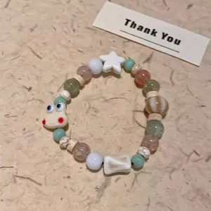 Detail of beaded bracelet with mint green pearls and a cute cartoon calf pendant