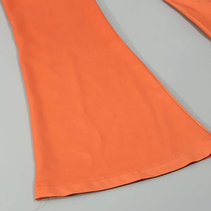 Détail du zoom sur l'ourlet cousu et le bas évasé d'un pantalon combinaison orange