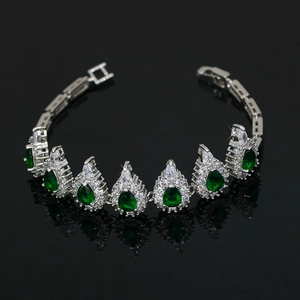 Detail of silver bracelet with pear-cut green gemstones and clear crystals on black surface