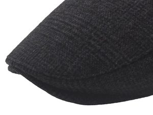 Close-up of the black tweed fabric texture and fine knit stitching on the flat cap