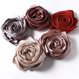 Detailed view of colorful satin headscarves folded into decorative silk rose shapes