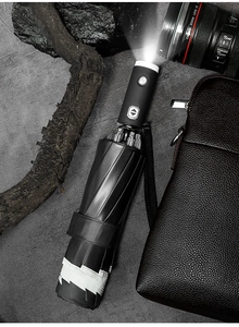 Detail of automatic umbrella handle with integrated LED flashlight and reflective safety strip