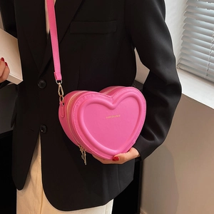 Dettaglio macro della borsa a cuore magenta con catena dorata e texture in pelle PU fine