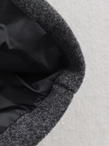 Close-up of charcoal wool fabric texture and black polyester lining of the long coat