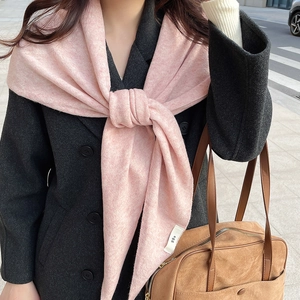 Detail eines rosa Strickschals mit weißem Egg-Etikett auf einem grauen Wollmantel