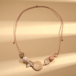 Detail of bohemian necklace with woven rattan disc and geometric wooden beads on beige cord