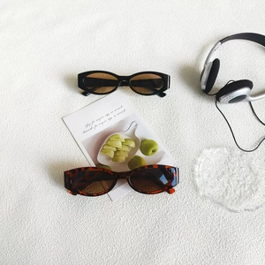 Retro cat-eye sunglasses in black and tortoiseshell finish on minimalist white background