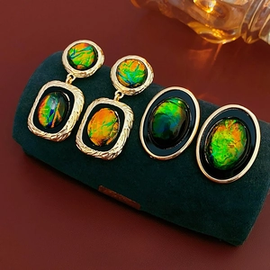 Golden metal earrings and jewelry set with colorful opal stones on dark display