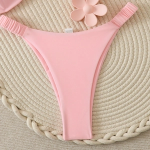 Détail du bas de bikini rose échancré avec étiquette de lavage sur tapis tissé