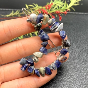 Detailed close-up of crescent moon hair clip with blue crystal stones and silver wire