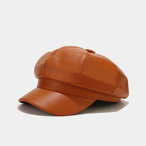 Detail of orange PU leather newsboy hat featuring textured multi-panel stitching