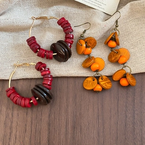 Détail de boucles d'oreilles bohèmes en perles de bois et noix de coco sur fond de jute