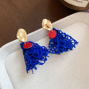 Detailed close-up of fan-shaped blue mesh fabric earrings on a cream fabric tray