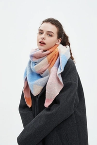Detail of soft plaid scarf in blue and pink worn as a triangular wrap by a model