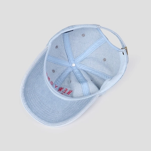 Detail view of washed denim baseball cap with six-panel construction and metal buckle