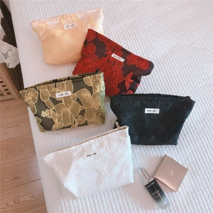 Detailed flat lay of five floral embossed lace cosmetic bags in various colors
