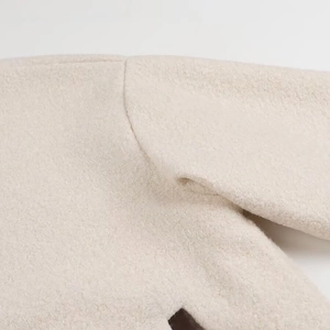 Macro shot of off-white faux shearling texture on round neck jacket shoulder and sleeve seam
