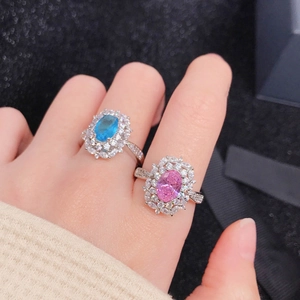 Close-up of pink and blue gemstone rings with zircon halo on model's hand