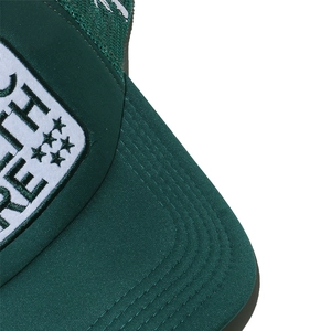 Detailed close-up of dark green trucker hat featuring white embroidered star patch